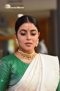 Actress Poorna in a white saree and green blouse posing for a photoshoot