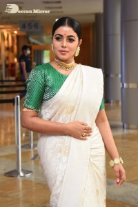 Actress Poorna in a white saree and green blouse posing for a photoshoot