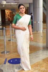 Actress Poorna in a white saree and green blouse posing for a photoshoot