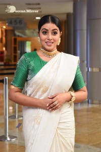 Actress Poorna in a white saree and green blouse posing for a photoshoot