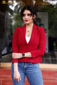 actress Ritika Singh in a red coat and blue denim jeans