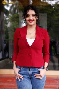 actress Ritika Singh in a red coat and blue denim jeans