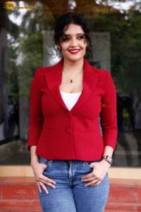 actress Ritika Singh in a red coat and blue denim jeans