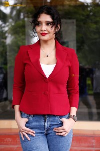 actress Ritika Singh in a red coat and blue denim jeans