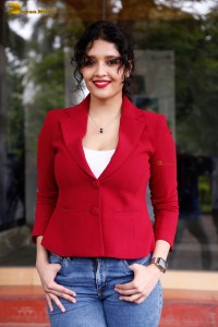 actress Ritika Singh in a red coat and blue denim jeans