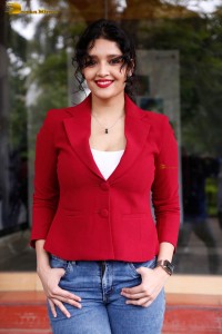 actress Ritika Singh in a red coat and blue denim jeans