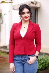 actress Ritika Singh in a red coat and blue denim jeans