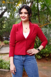 actress Ritika Singh in a red coat and blue denim jeans