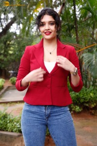 actress Ritika Singh in a red coat and blue denim jeans