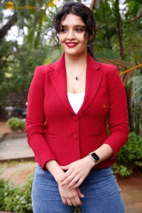 actress Ritika Singh in a red coat and blue denim jeans