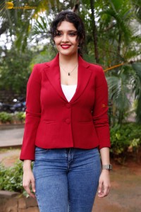 actress Ritika Singh in a red coat and blue denim jeans