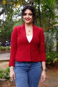 actress Ritika Singh in a red coat and blue denim jeans