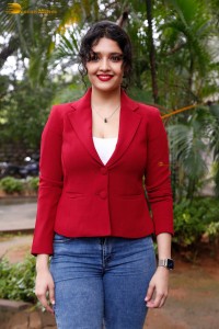actress Ritika Singh in a red coat and blue denim jeans