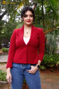 actress Ritika Singh in a red coat and blue denim jeans