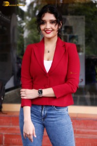 actress Ritika Singh in a red coat and blue denim jeans