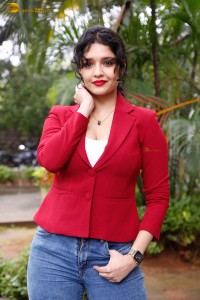 actress Ritika Singh in a red coat and blue denim jeans