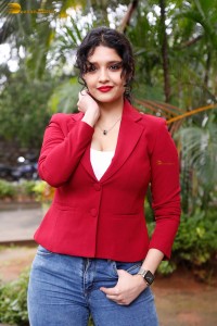 actress Ritika Singh in a red coat and blue denim jeans