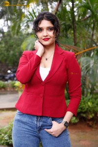 actress Ritika Singh in a red coat and blue denim jeans