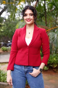 actress Ritika Singh in a red coat and blue denim jeans