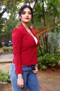 actress Ritika Singh in a red coat and blue denim jeans