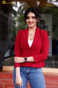 actress Ritika Singh in a red coat and blue denim jeans