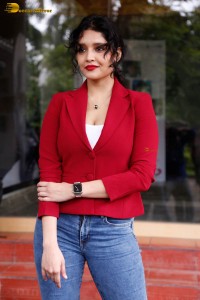 actress Ritika Singh in a red coat and blue denim jeans