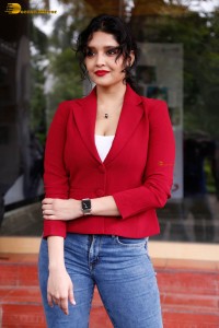 actress Ritika Singh in a red coat and blue denim jeans
