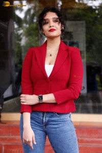 actress Ritika Singh in a red coat and blue denim jeans