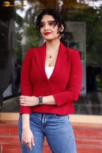 actress Ritika Singh in a red coat and blue denim jeans
