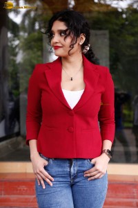 actress Ritika Singh in a red coat and blue denim jeans