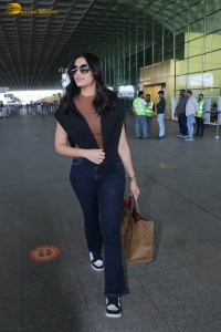actress saiee manjrekar in a dark orange top and black jeans at airport