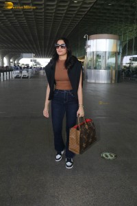 actress saiee manjrekar in a dark orange top and black jeans at airport