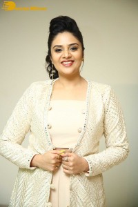 Sreemukhi posing for pictures in a white dress