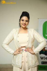 Sreemukhi posing for pictures in a white dress