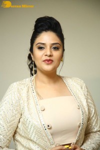 Sreemukhi posing for pictures in a white dress
