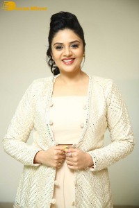 Sreemukhi posing for pictures in a white dress