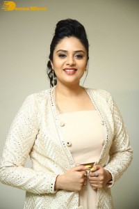 Sreemukhi posing for pictures in a white dress