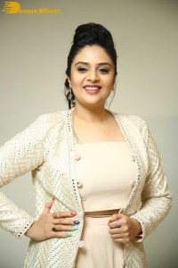 Sreemukhi posing for pictures in a white dress