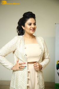 Sreemukhi posing for pictures in a white dress