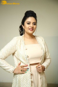 Sreemukhi posing for pictures in a white dress