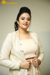 Sreemukhi posing for pictures in a white dress