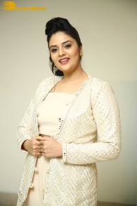 Sreemukhi posing for pictures in a white dress