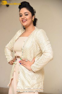 Sreemukhi posing for pictures in a white dress