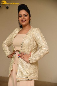 Sreemukhi posing for pictures in a white dress