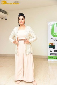 Sreemukhi posing for pictures in a white dress