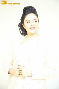 Sreemukhi posing for pictures in a white dress