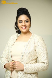 Sreemukhi posing for pictures in a white dress