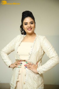 Sreemukhi posing for pictures in a white dress