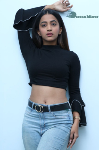 Actress Sruthi Shetty in a black top and blue jeans