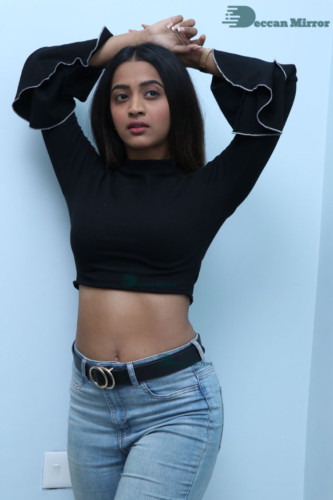Actress Sruthi Shetty in a black top and blue jeans
